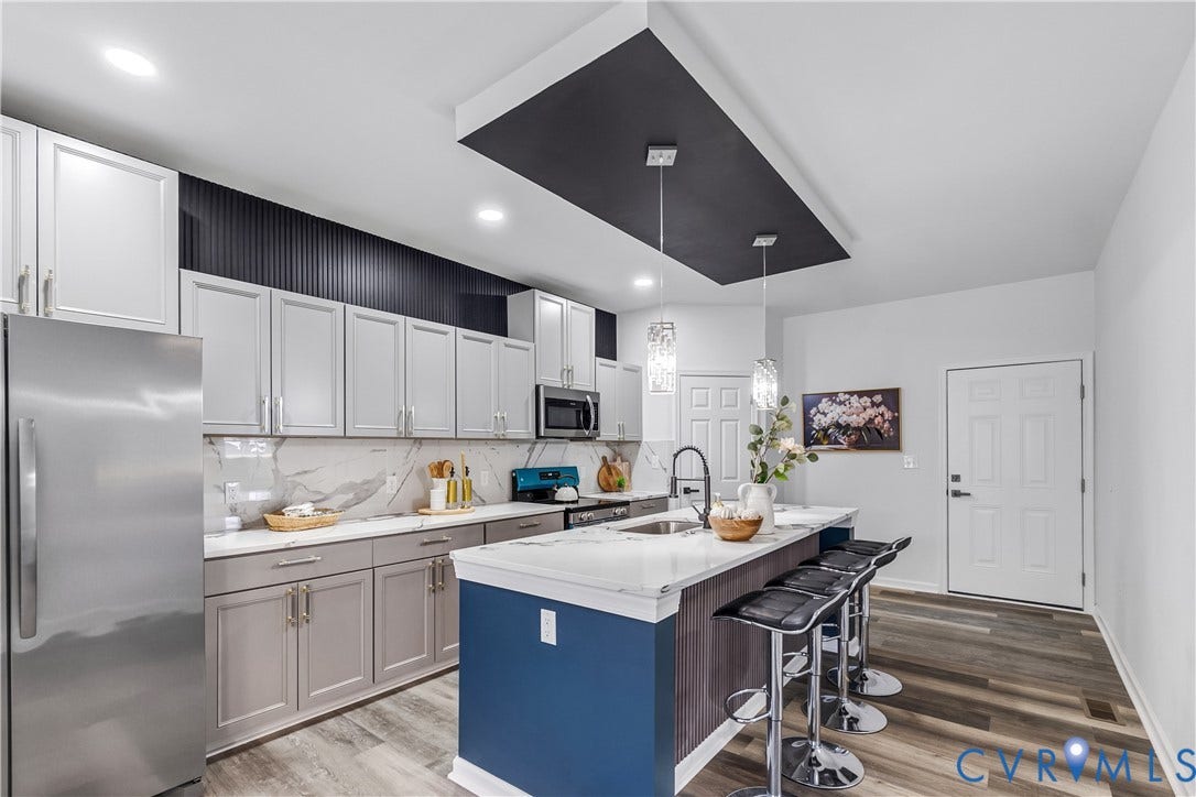 Kitchen featuring stainless steel appliances, white and gray cabinetry, white countertops, and wood-finish flooring