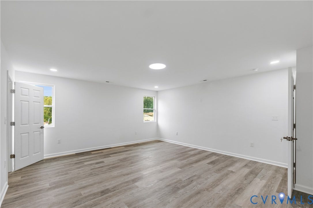 Spacious room featuring wood-finish flooring, white walls, and recessed lighting