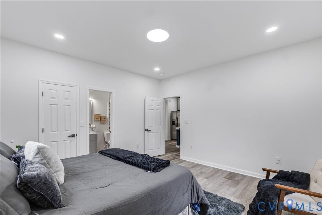 Recessed lighting with a circular skylight, wood-finish flooring, and white walls