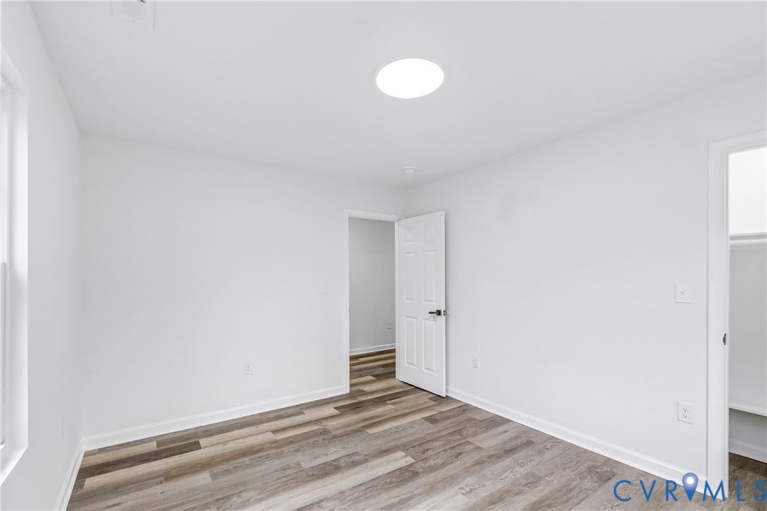 Recessed ceiling light, white interior walls, wood-finish flooring, and a window for natural light