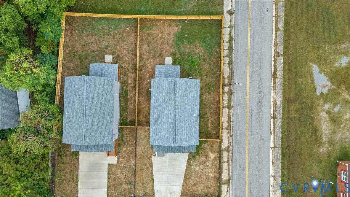 Two properties featuring gray shingle roofs, individual concrete driveways, and partial wood fencing