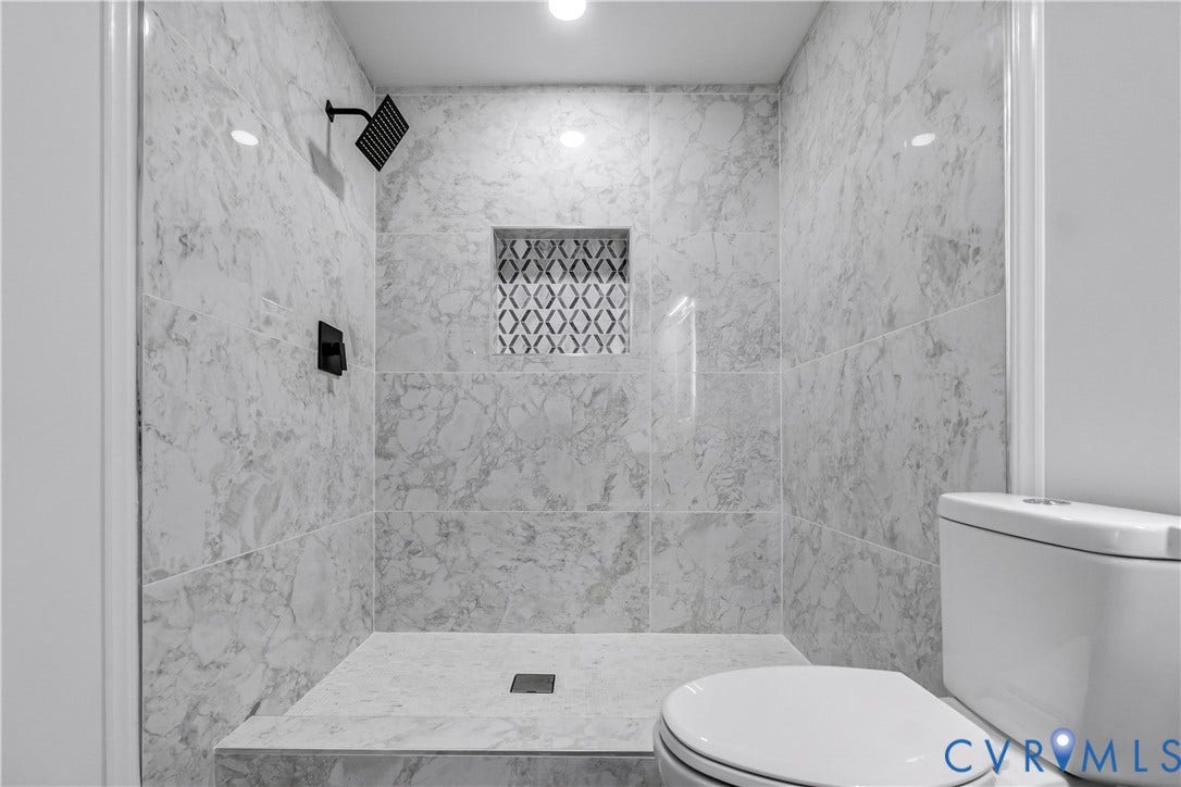 Marble-look tile shower with a recessed niche featuring patterned mosaic tile