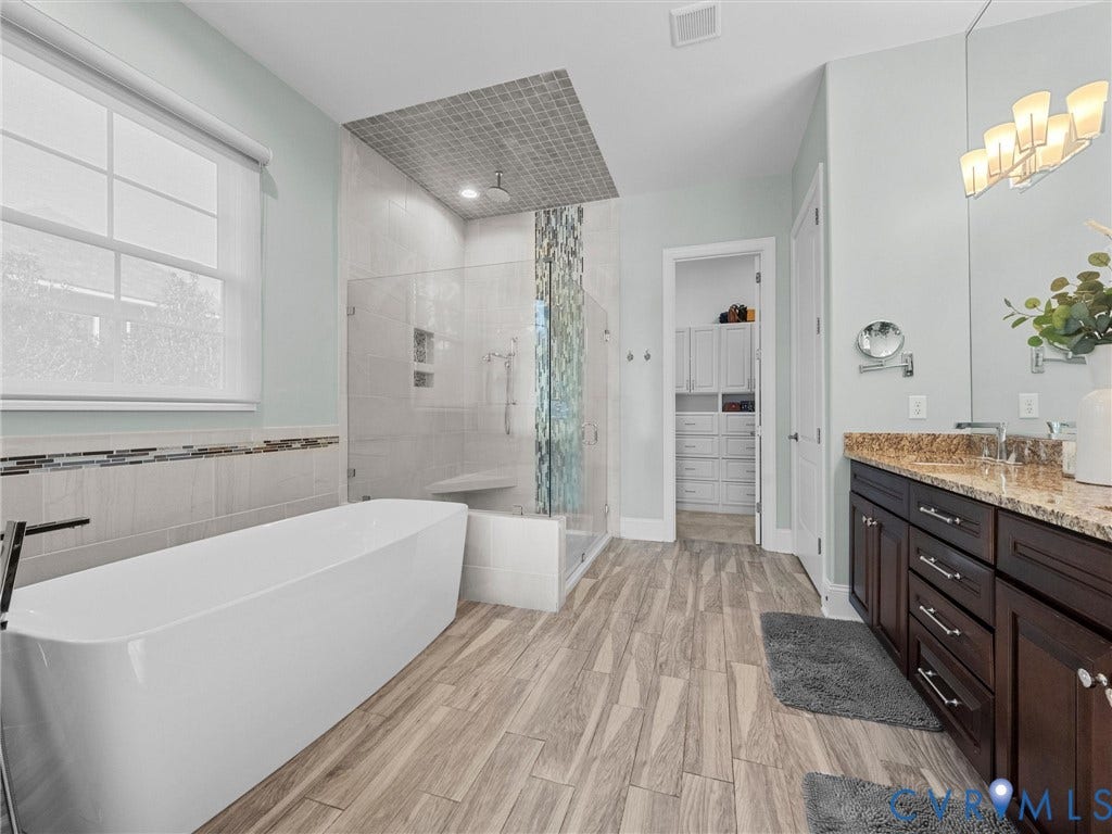 7750 Rock Cress Place, Chesterfield, VA 23120 Freestanding soaking tub, glass-enclosed walk-in shower with mosaic tile inlay, dark wood-finish cabinetry, natural stone countertop, and wood-finish flooring