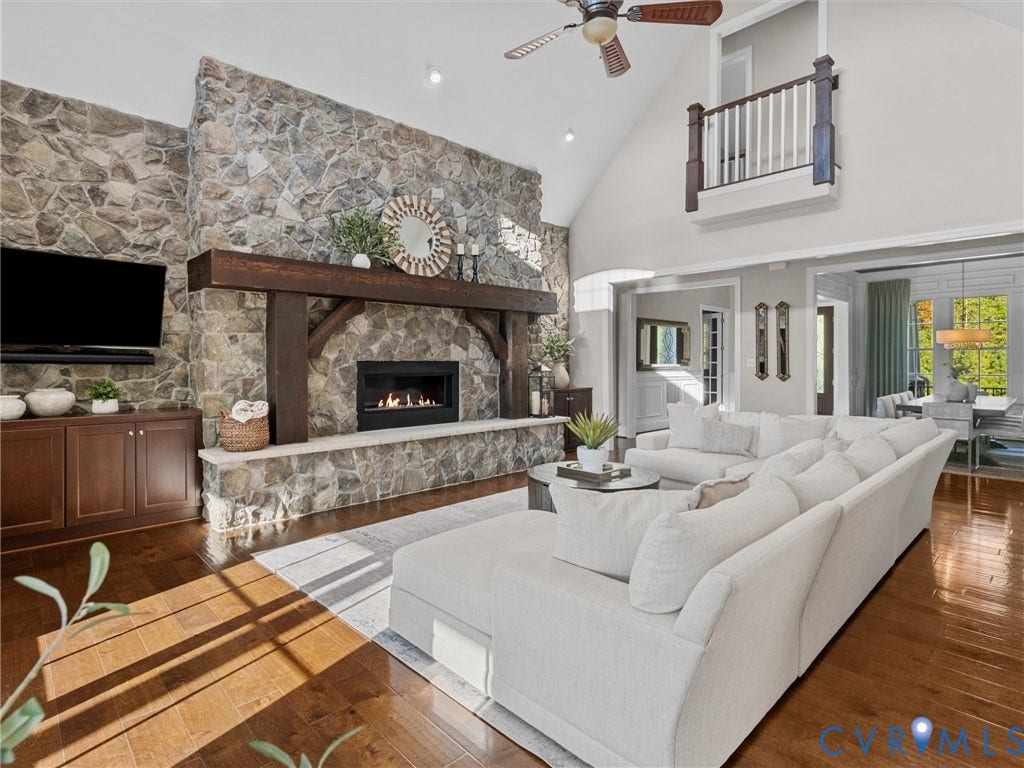7750 Rock Cress Place, Chesterfield, VA 23120 Vaulted ceilings featuring a full-height stone fireplace with a timber mantel, built-in cabinetry, wood-finish flooring, and a decorative interior balcony