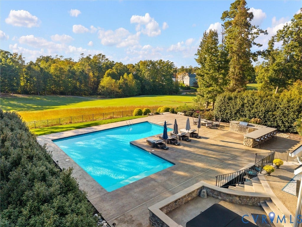 7750 Rock Cress Place, Chesterfield, VA 23120 L-shaped swimming pool with concrete decking, built-in stone-finished outdoor kitchen, and tiered retaining wall landscaping