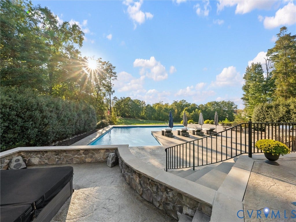 7750 Rock Cress Place, Chesterfield, VA 23120 In-ground pool with stone-veneer retaining walls, tiered stamped concrete patio, and custom black metal perimeter railing