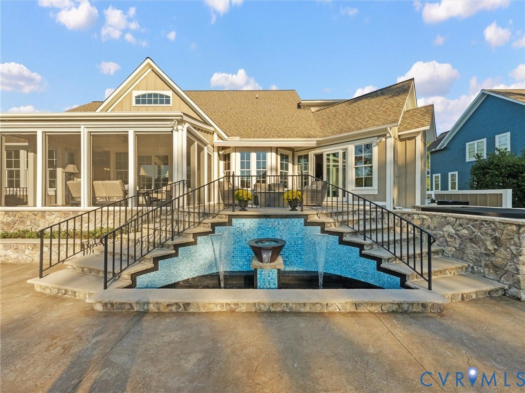 7750 Rock Cress Place, Chesterfield, VA 23120 Exterior rear patio featuring a tiered stone fountain with blue mosaic tile inlay, expansive concrete terrace, wraparound iron railings, and a screened enclosure with glass windows