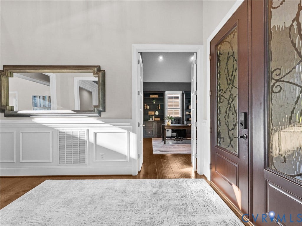7750 Rock Cress Place, Chesterfield, VA 23120 Foyer featuring wood-finish flooring, white wainscoting, double front doors with decorative glass inserts, and a wide doorway opening to a room with dark built-in shelving