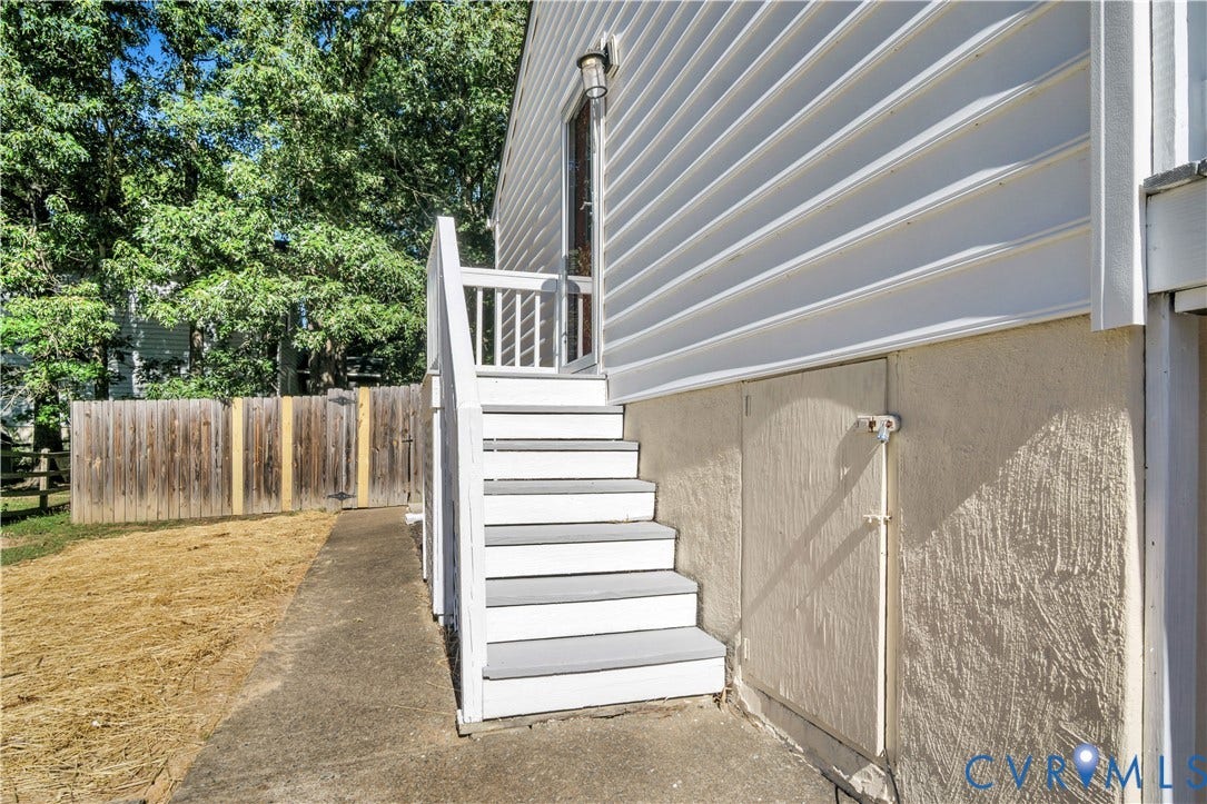 2724 Glen Point Circle, Henrico, VA 23233 Exterior featuring white siding, a white wooden staircase, a wooden privacy fence, and a concrete pathway