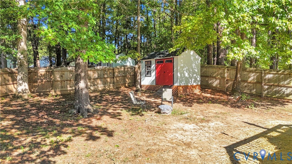 2724 Glen Point Circle, Henrico, VA 23233 Expansive backyard featuring a wood fence, mature trees, and a white storage shed with red doors
