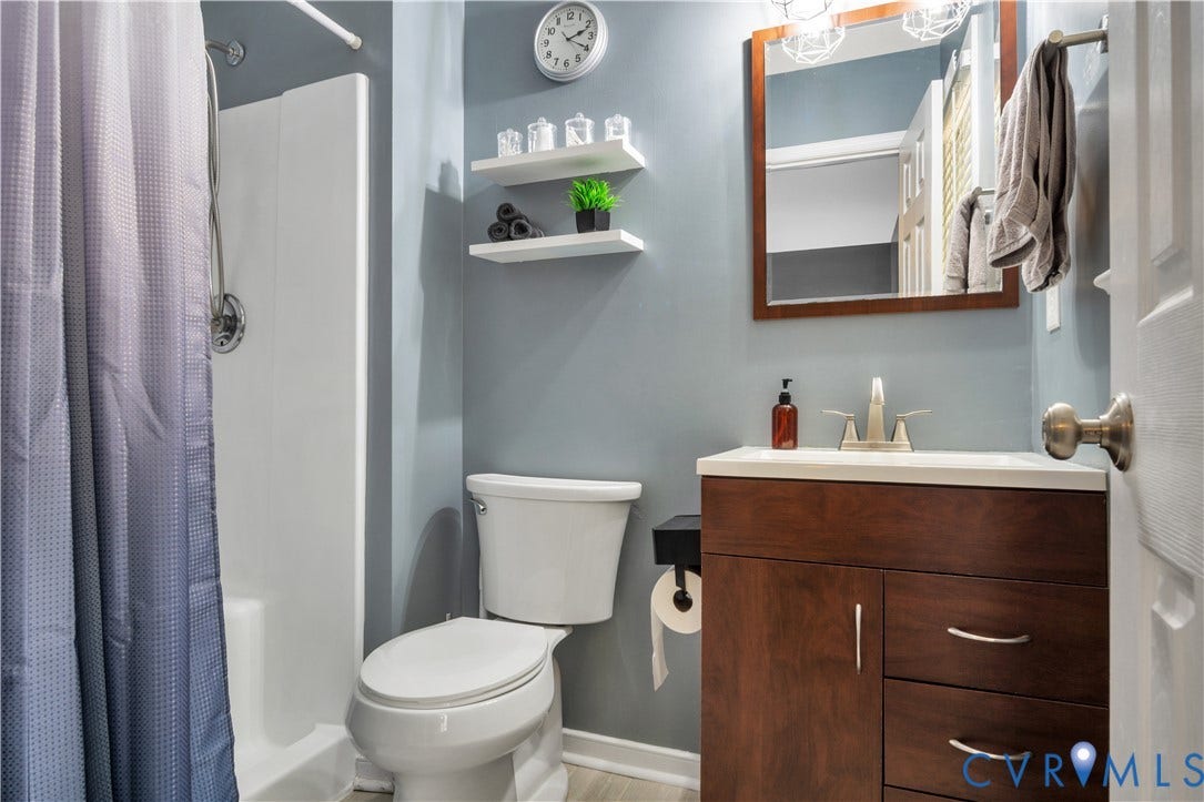 2724 Glen Point Circle, Henrico, VA 23233 Shower stall with a chrome-finish shower head, white toilet, wood-finish vanity with a white countertop, and wall-mounted mirror with integrated lighting