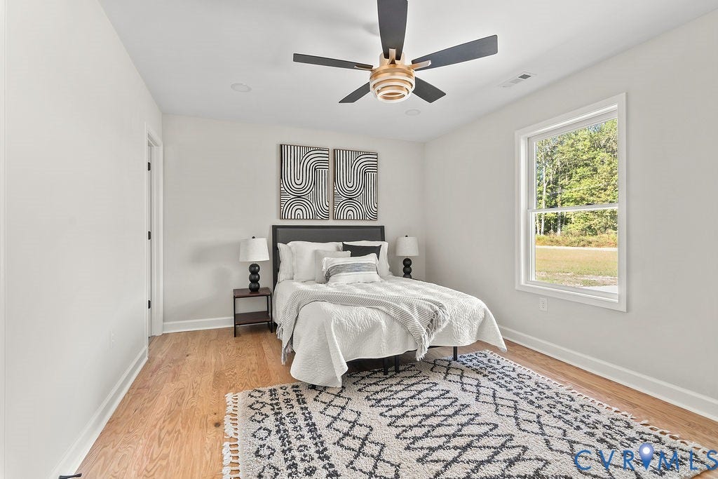 Wood-finish flooring, white walls, and a large window with natural light