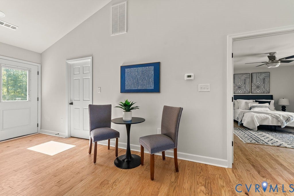 Wood-finish flooring throughout, white walls, and a recessed ceiling with a vent