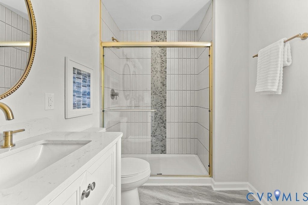 Vanity with integrated sink and gold-finish faucet, gold-frame mirror, and enclosed shower with gold-finish frame