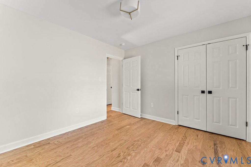 Hardwood flooring, painted walls, white trim, white paneled doors, and a ceiling-mounted light fixture