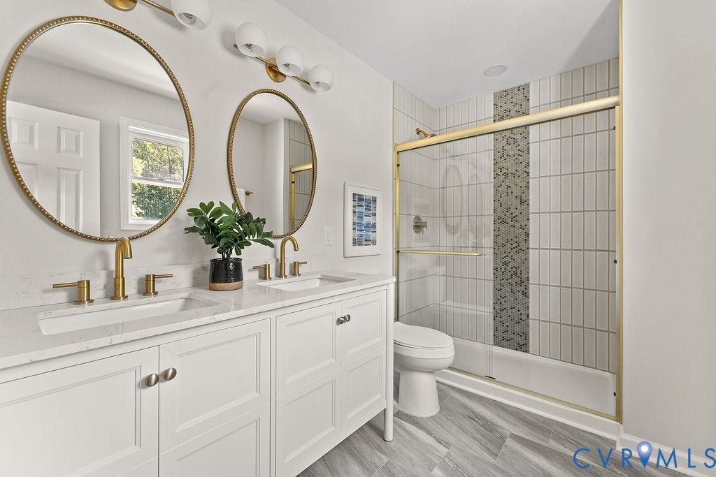 Double vanity with white cabinetry, gold-tone hardware, and integrated sinks