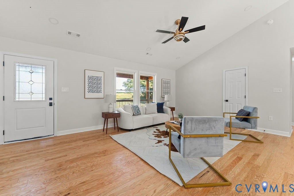 Vaulted ceiling with a ceiling fan, light wood-finish flooring, white paneled interior doors, recessed lighting, and large windows with exterior views