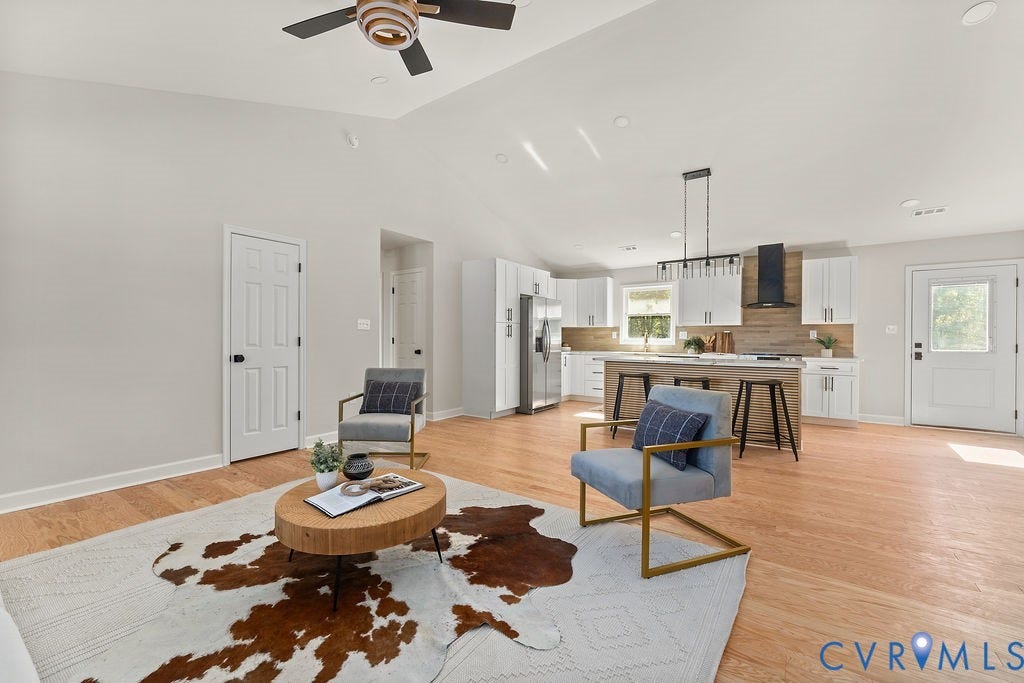 Vaulted ceiling, recessed lighting, wood-finish flooring, white shaker cabinetry, and a kitchen island with seating