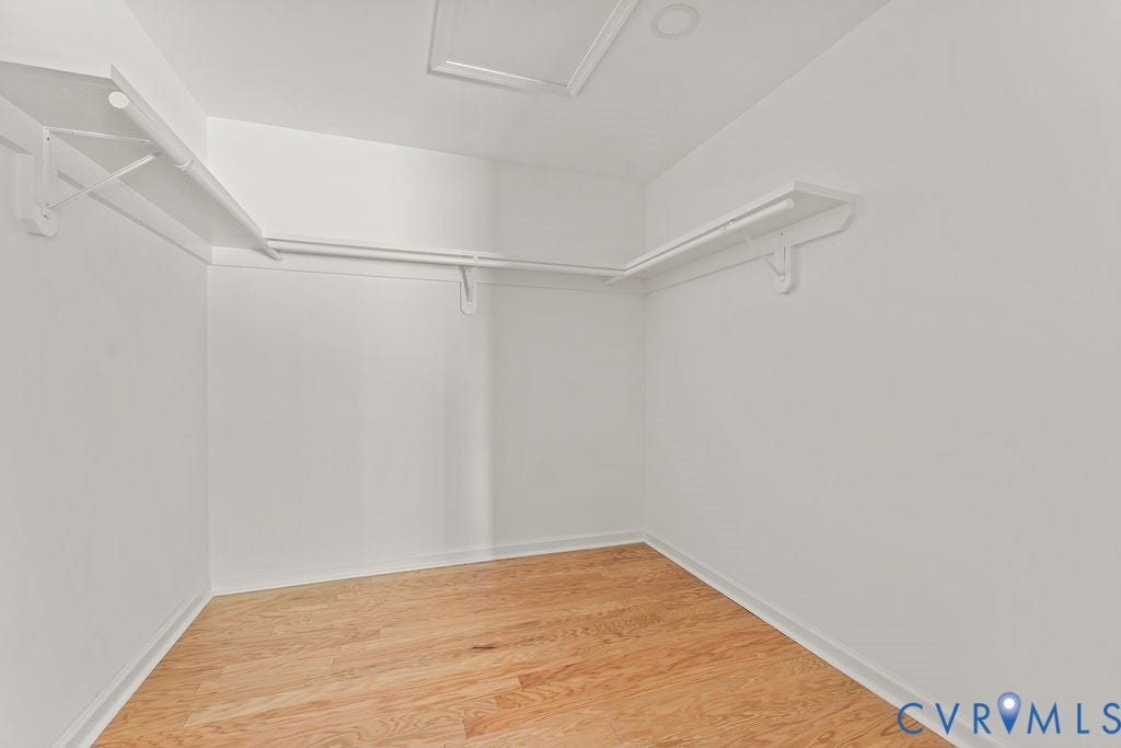 Wood-finish flooring, white walls, built-in shelving, and clothes rods