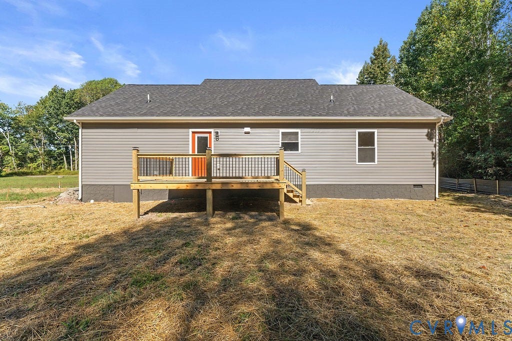 Rear exterior featuring gray siding, a dark shingle roof, and an elevated wood deck with black balusters