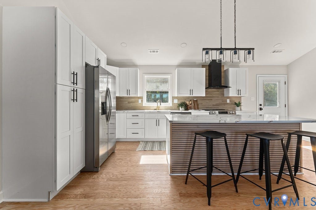 White cabinetry, stainless steel refrigerator, island with stone countertop, wood-finish flooring, and a black range hood
