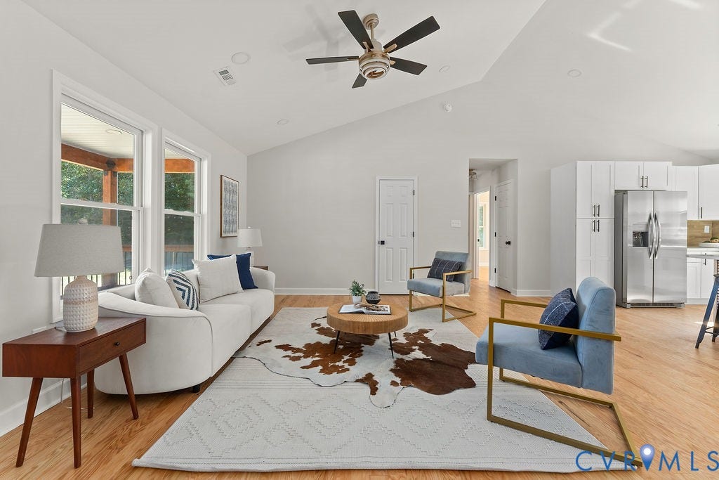 Vaulted ceiling with recessed lighting and a ceiling fan, light wood-finish flooring, white walls, and a partial view of the kitchen with white cabinetry and stainless steel appliances