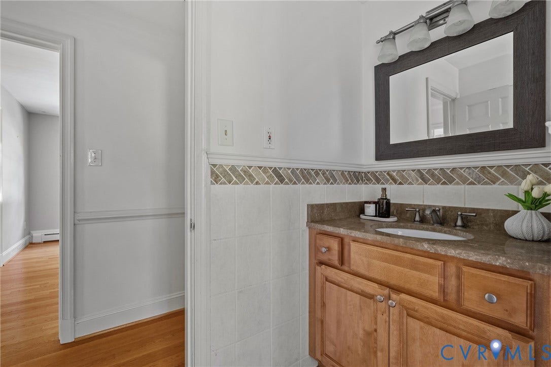 3700 Wakefield Road, Stratofrd Hills, Richmond, VA 23235 Bathroom vanity featuring a natural wood cabinet, stone countertop with an integrated oval sink, and a multi-light fixture