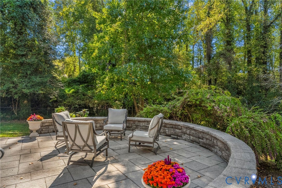 3700 Wakefield Road, Stratofrd Hills, Richmond, VA 23235 Curved stone retaining wall enclosing a paved patio area, set against a backdrop of mature trees