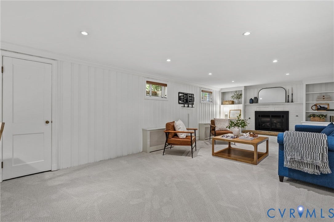 3700 Wakefield Road, Stratofrd Hills, Richmond, VA 23235 Interior space featuring vertical wood-panelled walls, recessed ceiling lighting, a stone-surround fireplace, and flanking built-in shelving