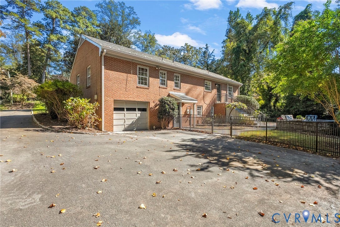 3700 Wakefield Road, Stratofrd Hills, Richmond, VA 23235 Two-story brick exterior featuring an attached one-car garage, asphalt driveway, metal fencing, and multi-pane windows