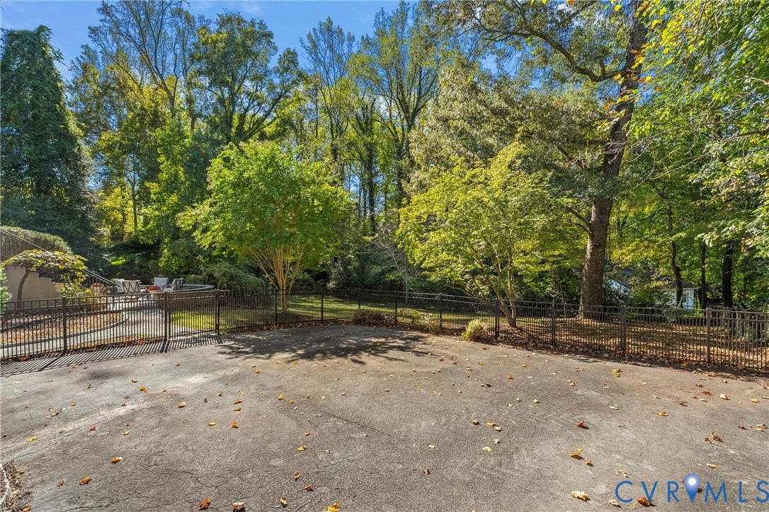 3700 Wakefield Road, Stratofrd Hills, Richmond, VA 23235 Spacious concrete patio enclosed by a metal perimeter fence, bordered by dense mature trees and varied deciduous foliage