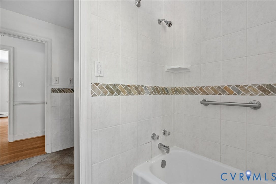 3700 Wakefield Road, Stratofrd Hills, Richmond, VA 23235 Bathtub with wall-mounted shower head, built-in shelving, herringbone tile accent border, and metal safety rail
