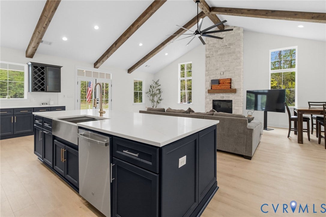 34356 Chinquapin Road, Waverly, VA 23890 Spacious kitchen featuring a large island with an undermount sink, stainless steel appliances, wood-finish flooring, and exposed ceiling beams