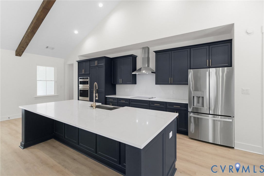 34356 Chinquapin Road, Waverly, VA 23890 Spacious kitchen featuring an expansive island with a sink, stainless steel appliances, custom cabinetry, and vaulted ceilings with an exposed beam