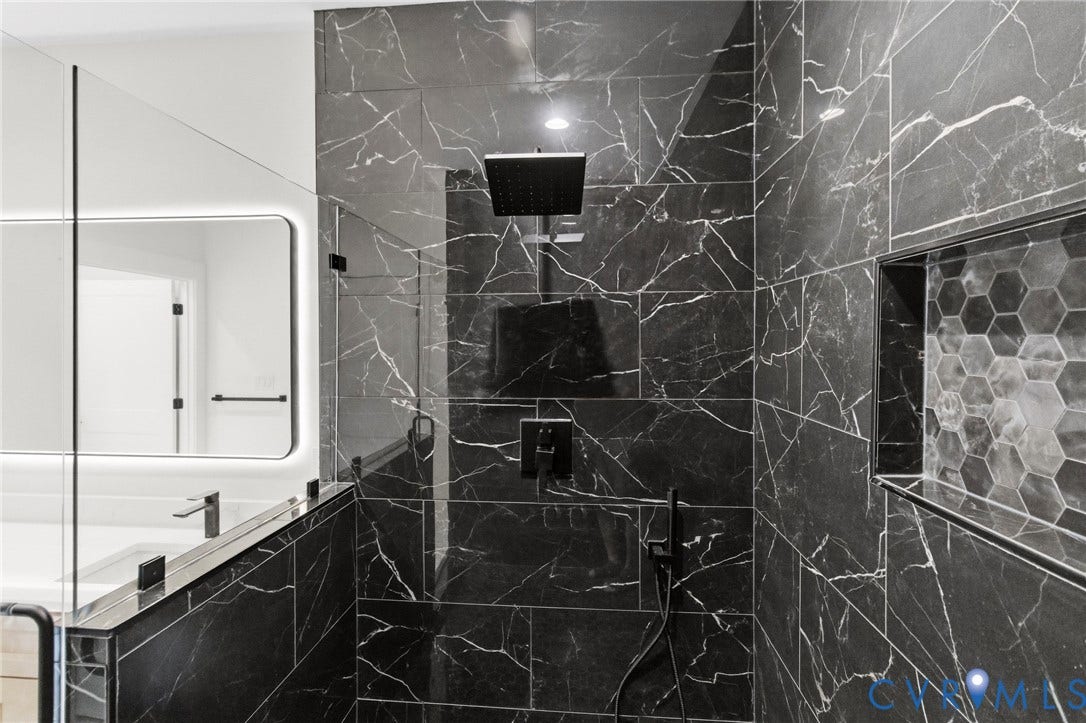 34356 Chinquapin Road, Waverly, VA 23890 Shower enclosure featuring large format black marbled tile, a built-in hexagonal tile niche, matte black fixtures, and a glass partition