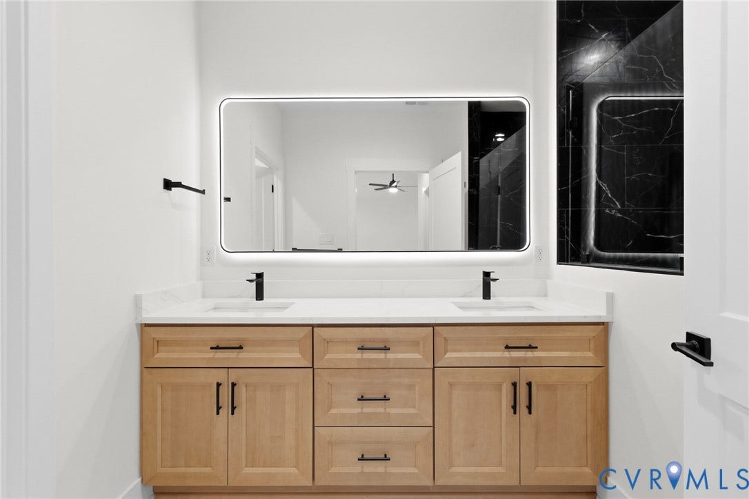 34356 Chinquapin Road, Waverly, VA 23890 Double vanity with light wood-finish cabinetry, white stone countertops, and matte black fixtures