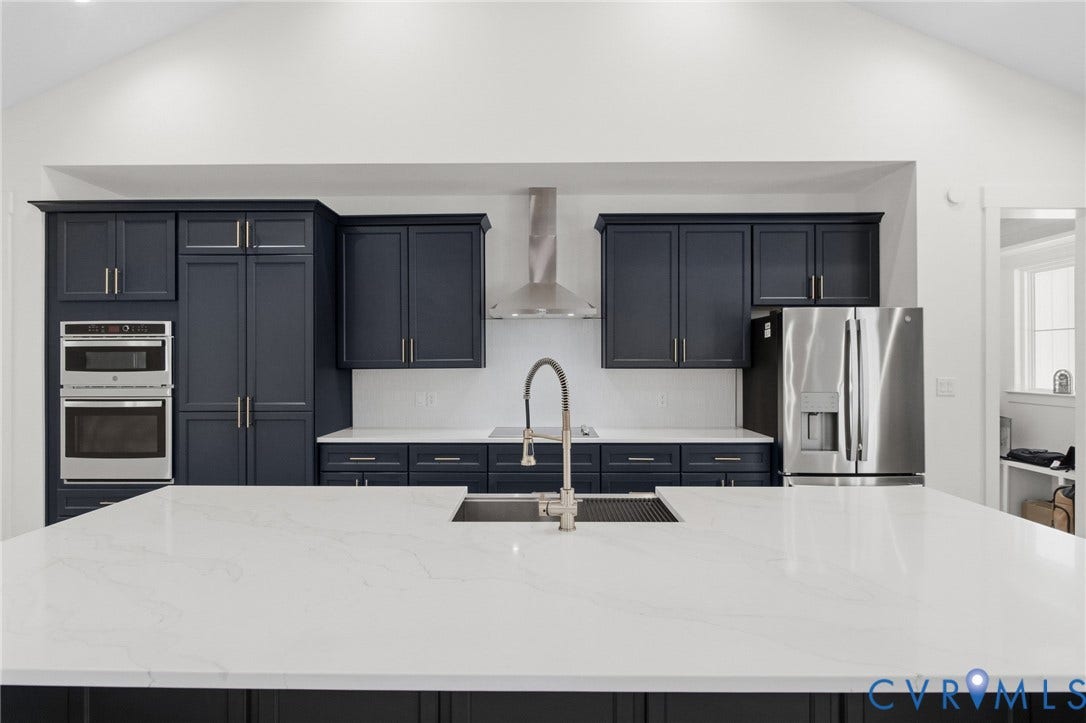 34356 Chinquapin Road, Waverly, VA 23890 Spacious kitchen featuring dark cabinetry, white countertops, built-in stainless steel appliances, a center island with sink, and high vaulted ceilings