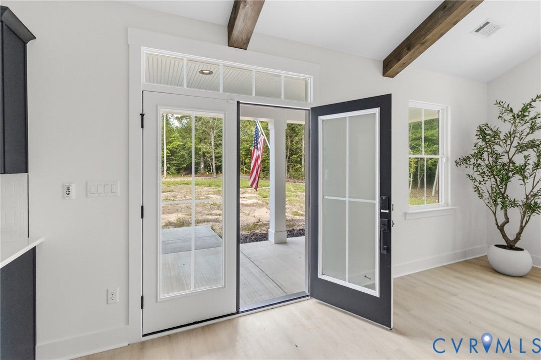 34356 Chinquapin Road, Waverly, VA 23890 Vaulted ceiling with exposed wood beams, wood-finish flooring, white walls, and a transom window above double glass-panel doors
