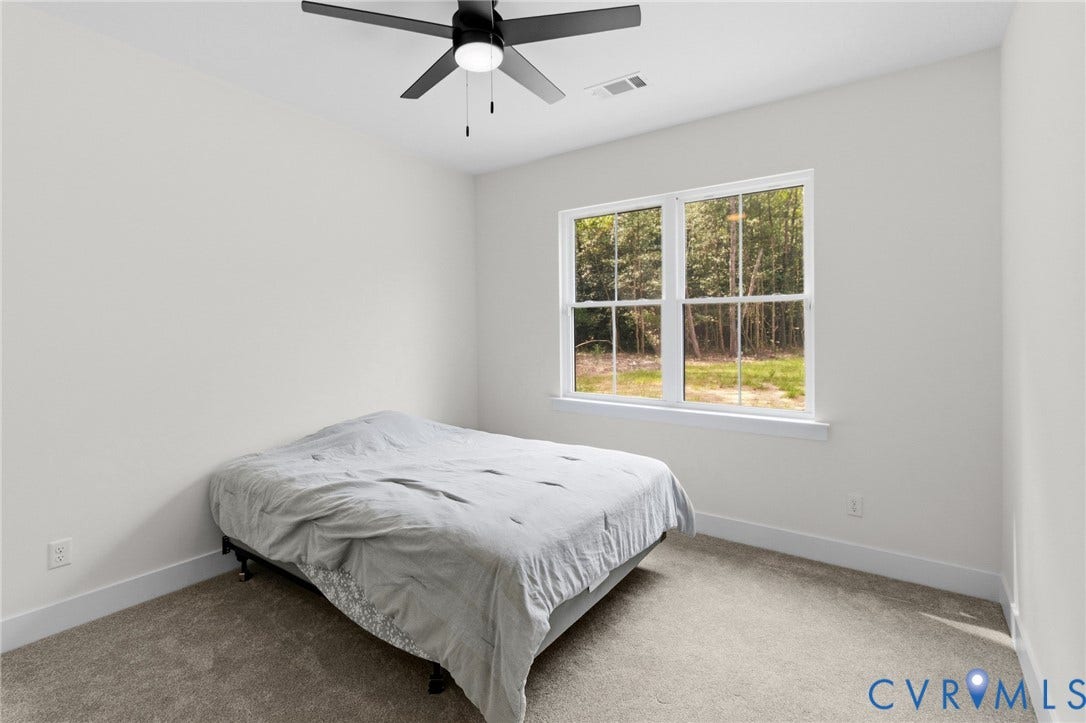 34356 Chinquapin Road, Waverly, VA 23890 Neutral wall paint, carpet flooring, a ceiling fan, and a large window