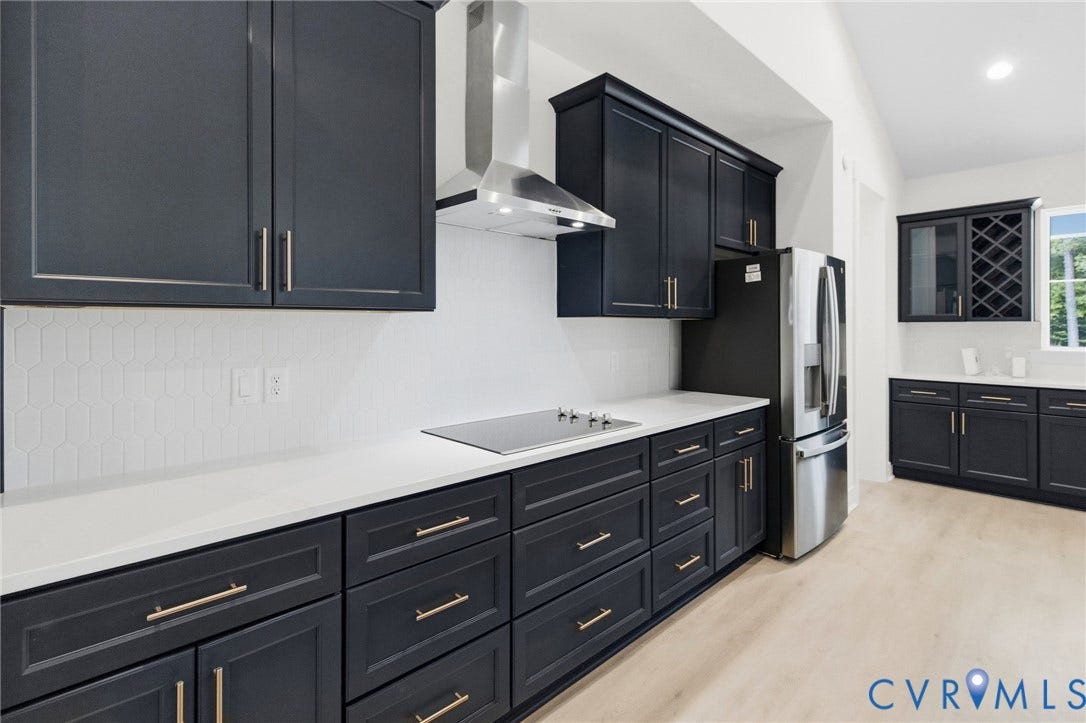 34356 Chinquapin Road, Waverly, VA 23890 Kitchen featuring dark cabinetry, stainless steel appliances, a white tile backsplash, light wood-finish flooring, and a vaulted ceiling