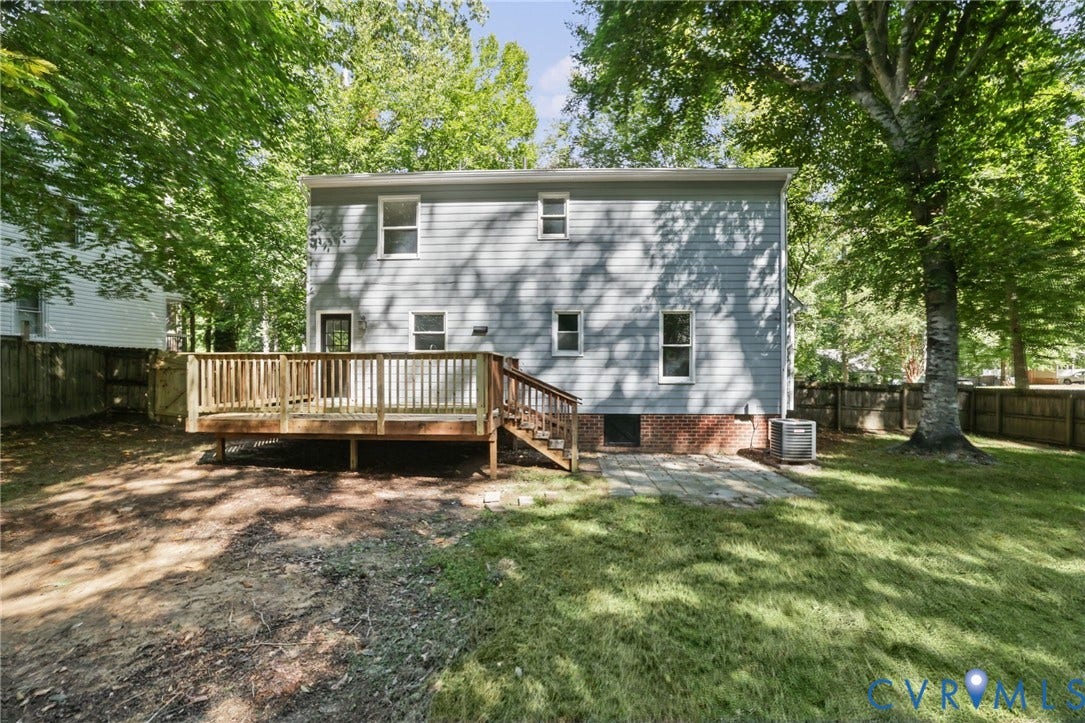 13811 Buck Rub Drive, Chesterfield, VA 23112 Rear exterior featuring a wood deck, wood privacy fence, mature trees, and a ground-level patio