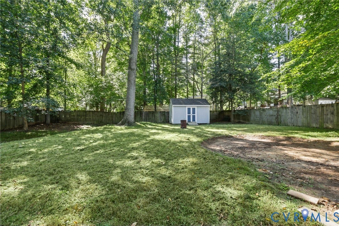 13811 Buck Rub Drive, Chesterfield, VA 23112 Expansive backyard featuring a natural wood fence, mature trees, a storage shed, and a section of exposed earth