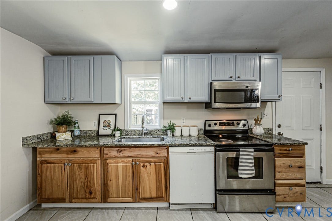 2011 Chicago Avenue, Richmond, VA 23224 Kitchen featuring two-tone cabinetry with wood-finish lower cabinets and light-painted upper cabinets, stone-surfaced countertops, stainless steel appliances, and tile flooring