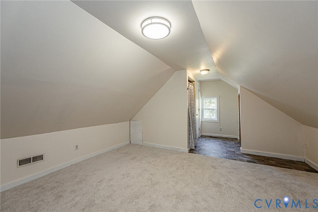 2011 Chicago Avenue, Richmond, VA 23224 Attic space featuring vaulted ceilings, neutral wall tones, wall-to-wall carpeting, dual flush-mount light fixtures, and a multi-pane window