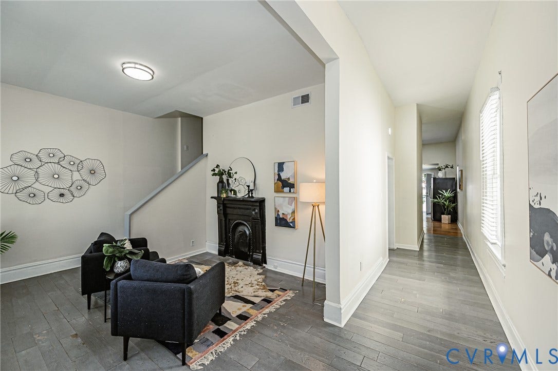 2011 Chicago Avenue, Richmond, VA 23224 Living area featuring wood-finish flooring, a decorative black cast-iron fireplace surround, a staircase with a partial wall, and a flush-mount ceiling light fixture