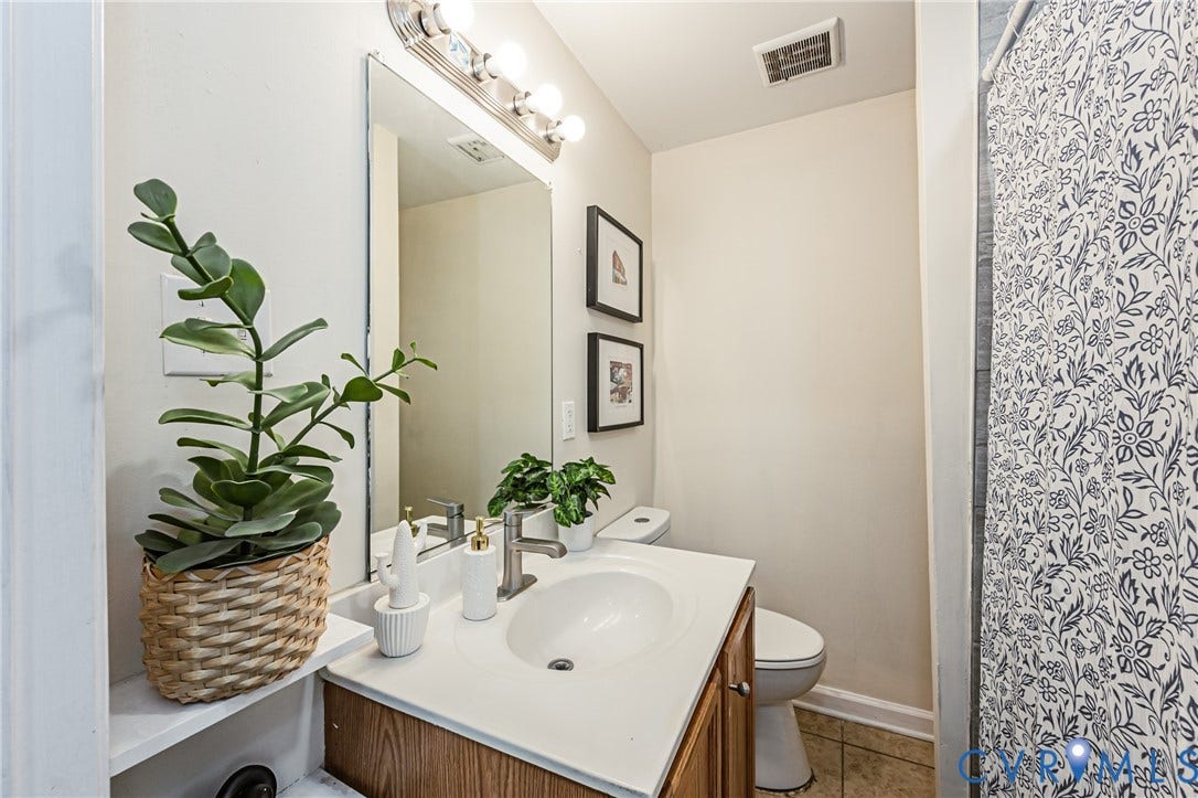 2011 Chicago Avenue, Richmond, VA 23224 Bathroom featuring a vanity with a white countertop and integrated oval sink, wood-finish cabinetry, a large wall-mounted mirror, and a multi-bulb light fixture