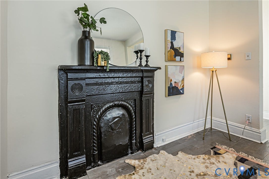 2011 Chicago Avenue, Richmond, VA 23224 Ornate black metal fireplace mantel featuring classical relief detailing and wood-finish flooring