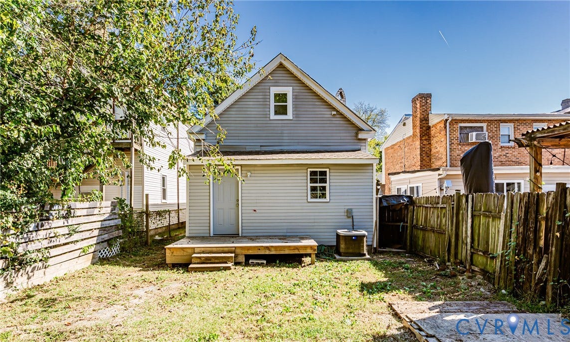 2011 Chicago Avenue, Richmond, VA 23224 Rear exterior featuring light grey siding, a raised wood deck with steps, and a fenced backyard