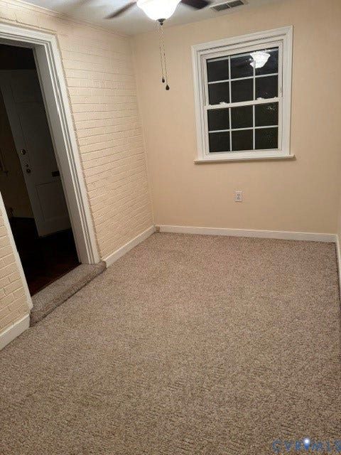 Textured wall covering, neutral wall paint, ceiling fan with integrated lighting, window with grid pattern, and carpet flooring