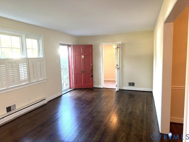 Wood-finish flooring, white plantation shutters, and a vibrant red entry door